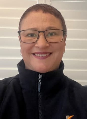 a woman with brown hair tightly pulled back and glasses is wearing a black top